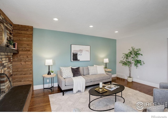 living area featuring baseboards, wood finished floors, recessed lighting, and a textured ceiling