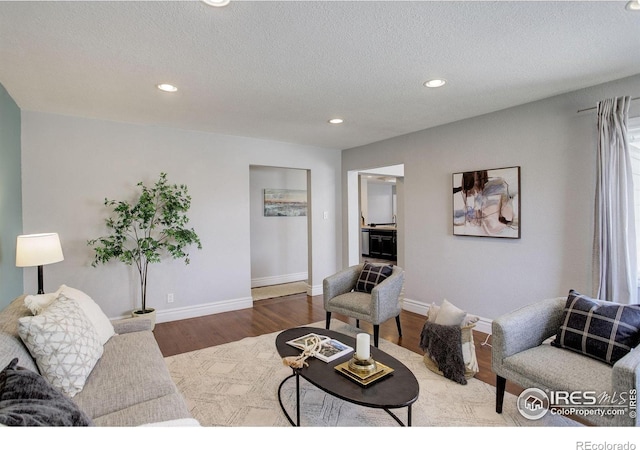 living room with recessed lighting, baseboards, wood finished floors, and a textured ceiling