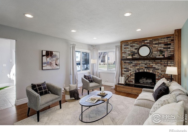 living room with wood finished floors, baseboards, a textured ceiling, recessed lighting, and a fireplace
