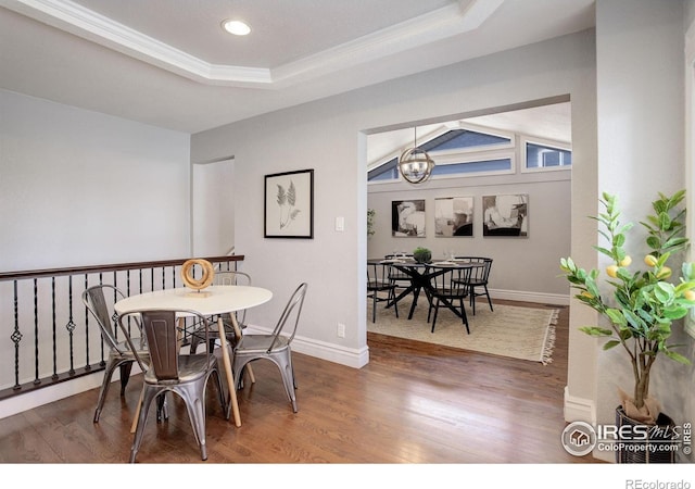dining space featuring a chandelier, wood finished floors, a raised ceiling, baseboards, and crown molding