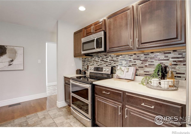 kitchen with stainless steel appliances, decorative backsplash, light countertops, and recessed lighting