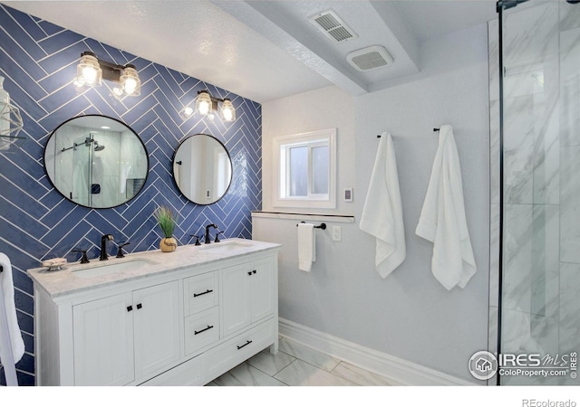 full bathroom with marble finish flooring, double vanity, baseboards, and a shower