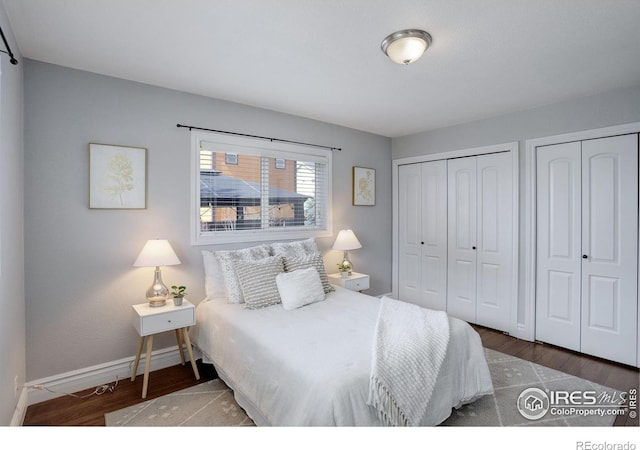 bedroom featuring wood finished floors, multiple closets, and baseboards