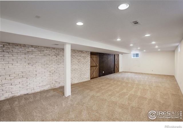 finished below grade area featuring carpet, recessed lighting, and brick wall