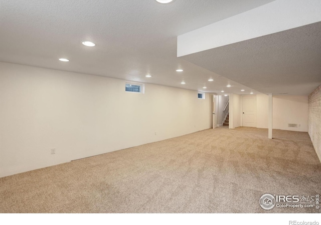 finished basement featuring carpet, recessed lighting, stairs, and a textured ceiling