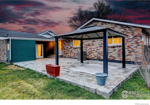patio terrace at dusk featuring a gazebo, central AC unit, and a lawn