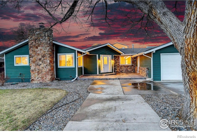 mid-century inspired home featuring a chimney, covered porch, and an attached garage