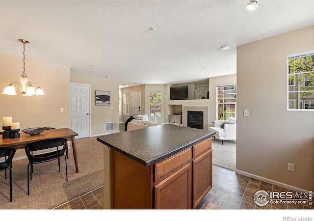 14300 Waterside Ln Unit V1, Broomfield, CO 80023 - kitchen featuring dark countertops, a fireplace, a chandelier, baseboards, and dark colored carpet