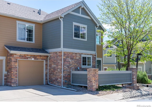 14300 Waterside Ln Unit V1, Broomfield, CO 80023 - view of front facade with a garage, roof with shingles, stone siding, and concrete driveway