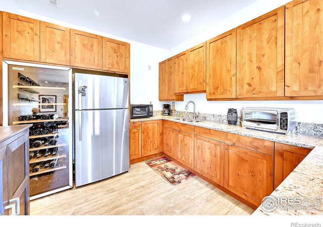 278 Clark Rd, Bailey, CO 80421 - kitchen with freestanding refrigerator, black microwave, light wood-style flooring, and light stone countertops