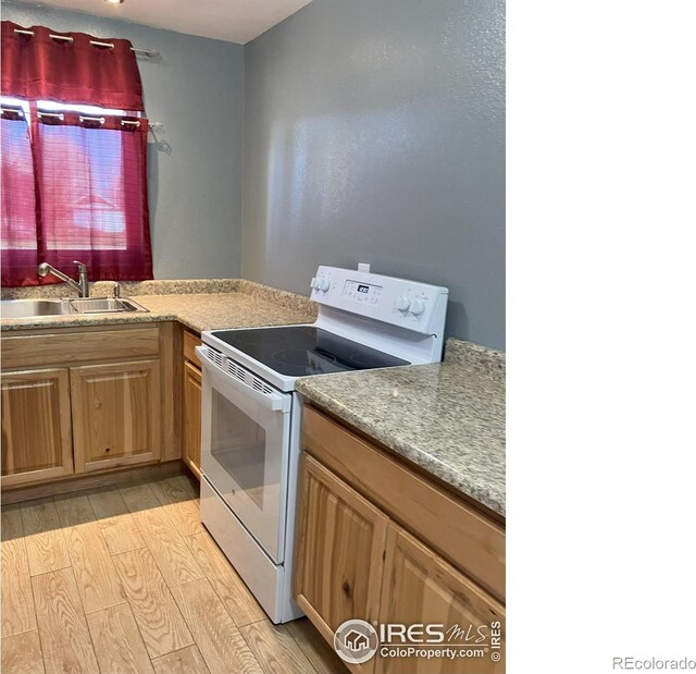210 S Bowman Ave, Holyoke, CO 80734 - kitchen with white range with electric stovetop, a sink, light wood finished floors, and light countertops