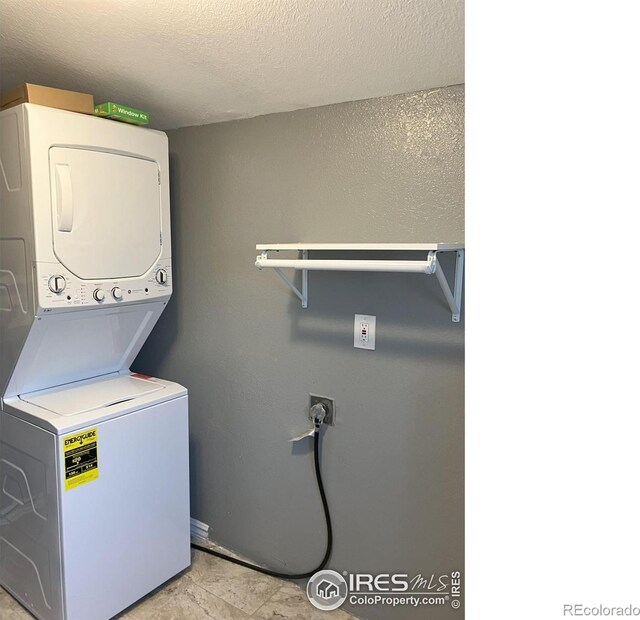 210 S Bowman Ave, Holyoke, CO 80734 - laundry area with stacked washer / drying machine, a textured ceiling, and baseboards