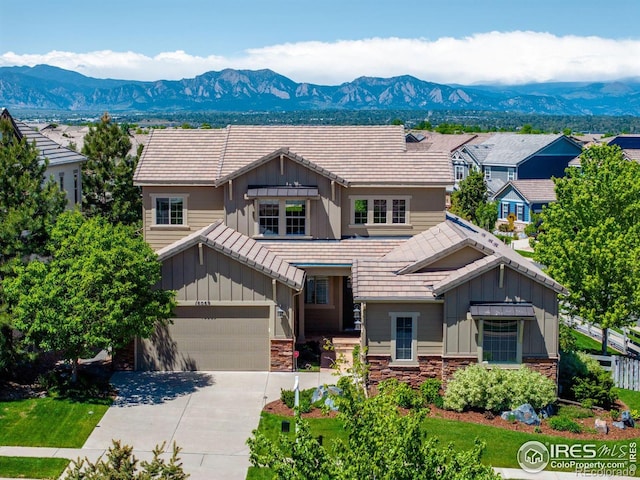 16069 Pikes Peak Dr, Broomfield, CO 80023 - craftsman-style home with board and batten siding, stone siding, a mountain view, concrete driveway, and a tiled roof