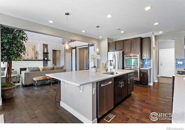 16069 Pikes Peak Dr, Broomfield, CO 80023 - kitchen featuring stainless steel appliances, a sink, dark brown cabinets, dark wood finished floors, and an island with sink