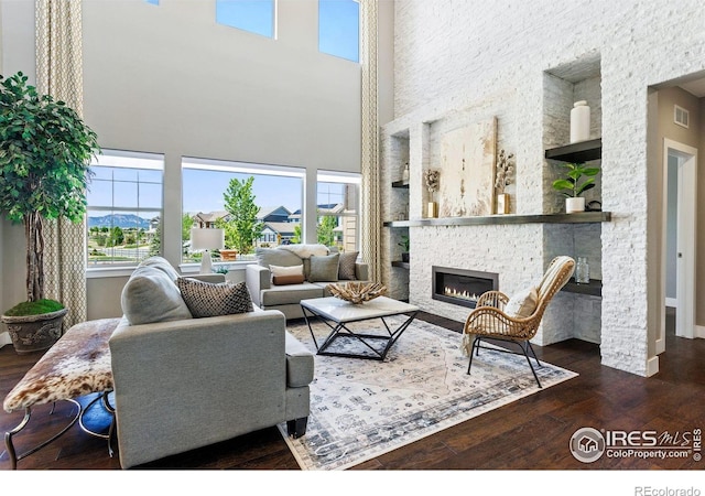 16069 Pikes Peak Dr, Broomfield, CO 80023 - living room featuring wood-type flooring, a towering ceiling, a fireplace, built in features, and baseboards