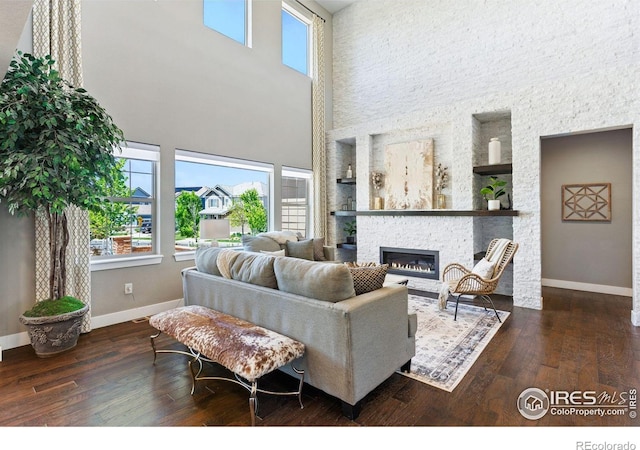 16069 Pikes Peak Dr, Broomfield, CO 80023 - living room featuring baseboards, a towering ceiling, hardwood / wood-style flooring, a fireplace, and built in features