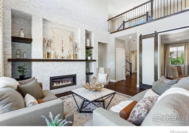 16069 Pikes Peak Dr, Broomfield, CO 80023 - living room featuring a barn door, a fireplace, wood finished floors, baseboards, and a towering ceiling
