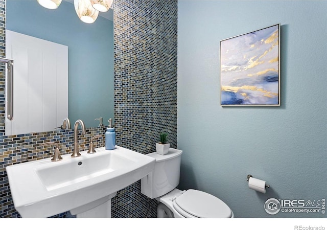 16069 Pikes Peak Dr, Broomfield, CO 80023 - half bath featuring a sink, toilet, and tasteful backsplash