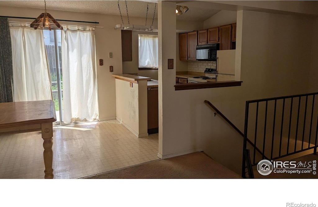 kitchen featuring white appliances, healthy amount of natural light, decorative backsplash, and baseboards