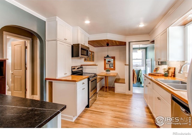 628 Endicott St, Fort Collins, CO 80524 - kitchen featuring appliances with stainless steel finishes, light wood-style floors, a sink, white cabinets, and decorative backsplash