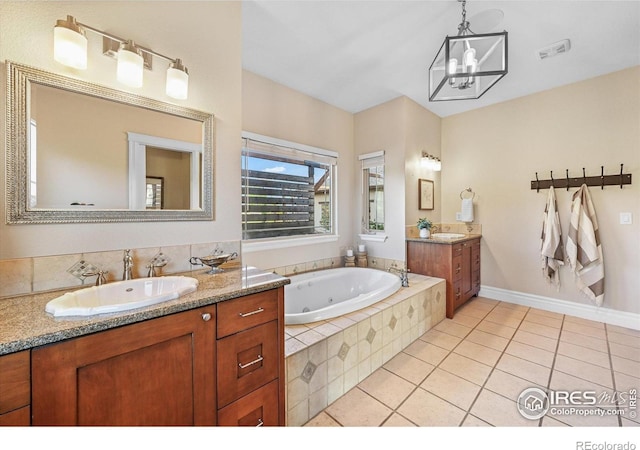 full bathroom with tile patterned flooring, two vanities, a jetted tub, a chandelier, and baseboards