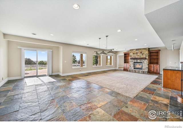 unfurnished living room with stone tile floors, baseboards, a fireplace, and recessed lighting