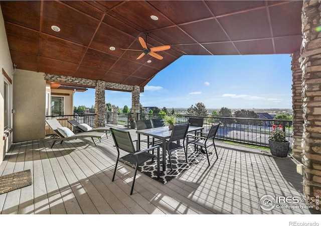 wooden terrace with outdoor dining space and ceiling fan