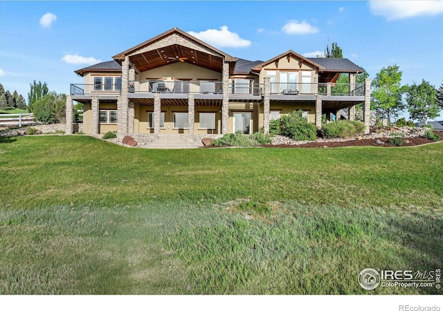 rear view of property featuring a yard, stucco siding, and stone siding