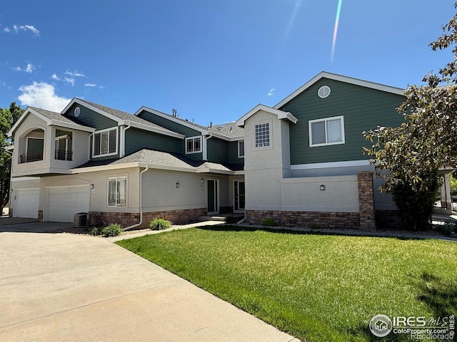 traditional-style home featuring an attached garage, a front lawn, driveway, stucco siding, and roof with shingles