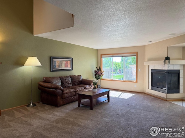 carpeted living room featuring a textured ceiling, baseboards, and a tile fireplace
