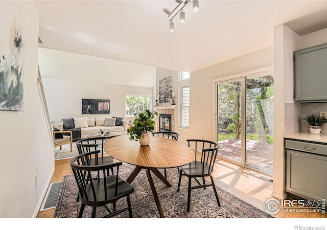 dining area featuring light wood-style flooring, a tile fireplace, and baseboards
