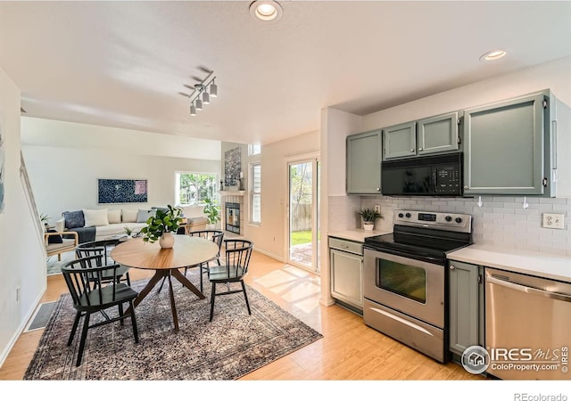 kitchen featuring stainless steel appliances, light wood-style flooring, light countertops, decorative backsplash, and baseboards