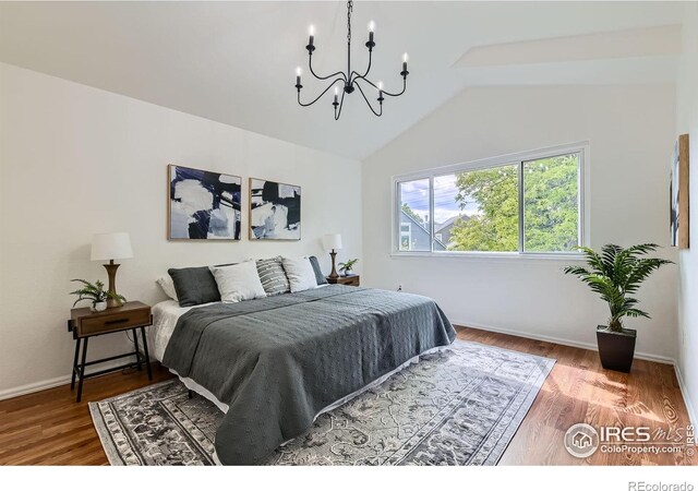 bedroom featuring a chandelier, vaulted ceiling, wood finished floors, and baseboards
