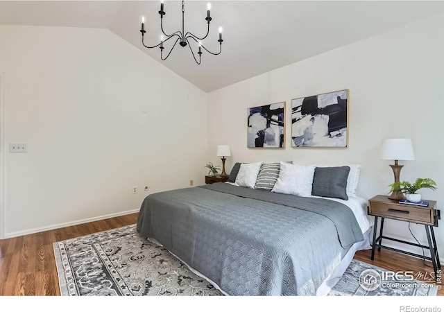 bedroom with a chandelier, lofted ceiling, and wood finished floors