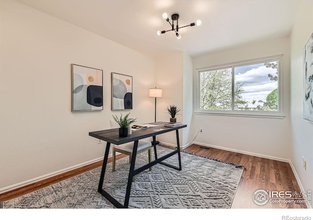 office space with a chandelier, wood finished floors, and baseboards