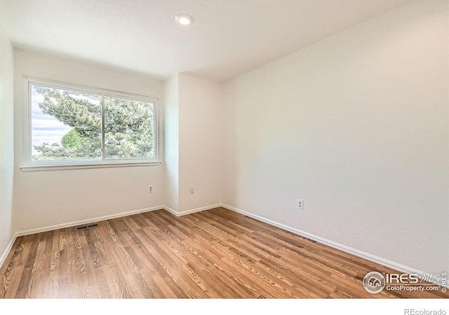 spare room featuring light wood-style flooring, baseboards, and recessed lighting