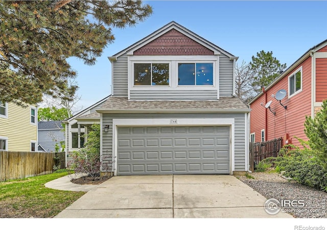 traditional-style house featuring fence, driveway, an attached garage, and a shingled roof