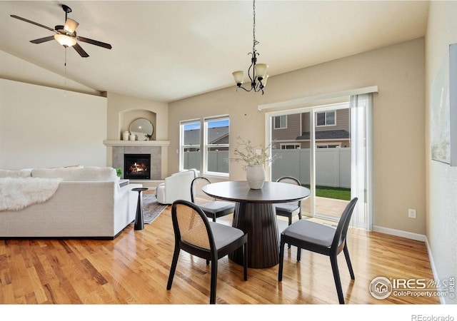 3933 Mount Hope St, Wellington, CO 80549 - dining room with light wood-type flooring, a chandelier, a lit fireplace, a ceiling fan, and baseboards