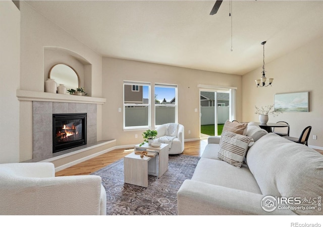 3933 Mount Hope St, Wellington, CO 80549 - living area featuring wood finished floors, a chandelier, a tile fireplace, lofted ceiling, and baseboards