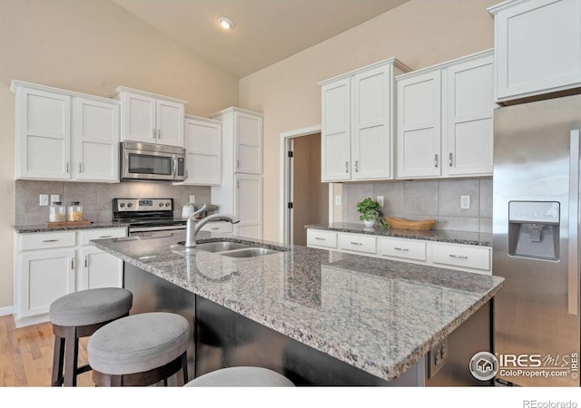 3933 Mount Hope St, Wellington, CO 80549 - kitchen with appliances with stainless steel finishes, a sink, tasteful backsplash, white cabinets, and lofted ceiling