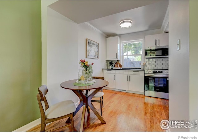 1235 Leyden St, Denver, CO 80220 - kitchen with stainless steel appliances, dark countertops, light wood finished floors, tasteful backsplash, and crown molding