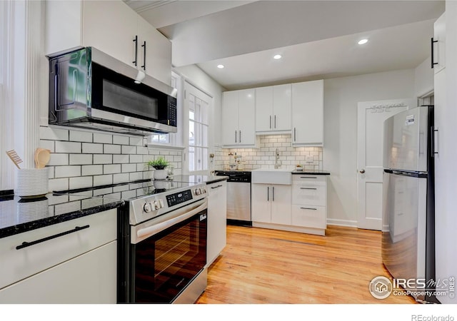 1235 Leyden St, Denver, CO 80220 - kitchen featuring stainless steel appliances, a sink, light wood finished floors, white cabinets, and backsplash