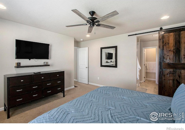 bedroom with recessed lighting, baseboards, light carpet, a barn door, and ensuite bathroom