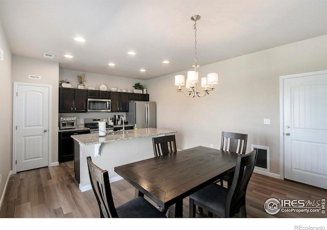 dining space with wood finished floors, a chandelier, recessed lighting, and baseboards