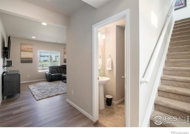 stairway with wood finished floors, baseboards, and recessed lighting