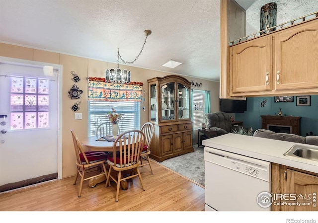 kitchen with white dishwasher, light wood-style flooring, a chandelier, light brown cabinets, and a textured ceiling