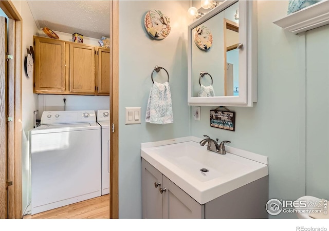 bathroom featuring separate washer and dryer, wood finished floors, vanity, and a textured ceiling