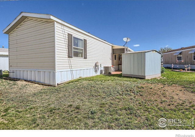 view of side of property featuring a yard, central AC, an outbuilding, and a storage shed