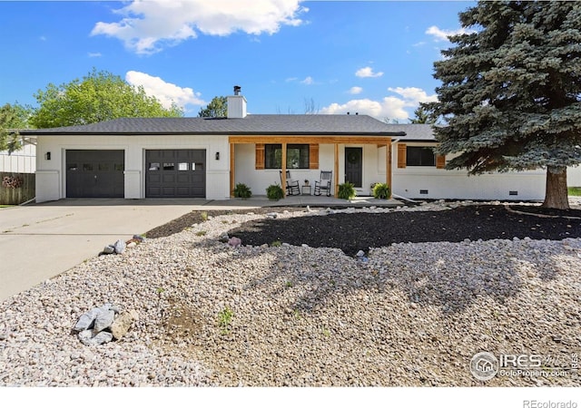 ranch-style house featuring covered porch, an attached garage, driveway, a chimney, and crawl space