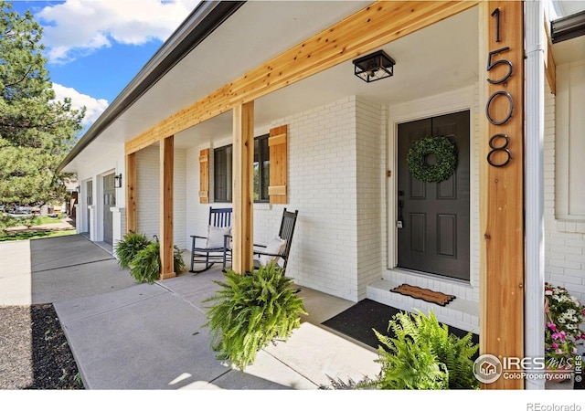entrance to property featuring covered porch and brick siding